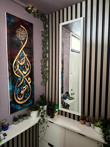 a mirror on a wall with a painting and plants at Koselig leilighet in Stavanger