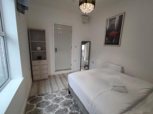 a white bedroom with a bed and a chandelier at New Guest House, Individual Ensuite Rooms with Comfortable Double Beds, TV and WiFi in Luton