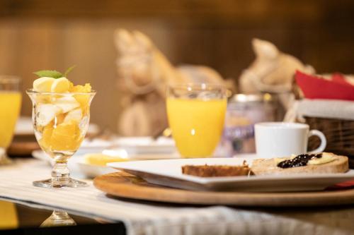 a table with a plate of food and two glasses of orange juice at Au Rascard in Brusson