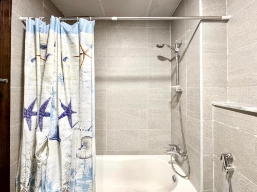 a bathroom with a shower curtain and a tub at Al Manara Premium Cozy Studio in Dubai