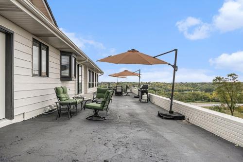 a patio with chairs and an umbrella on a house at Majestic VIEWS FunAmenities & Best for Huge Group in Council Bluffs