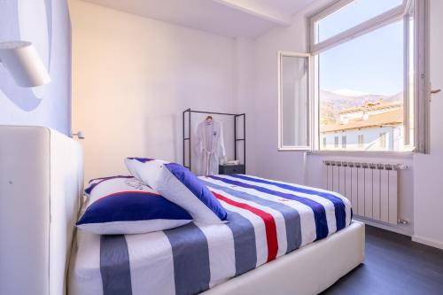 a bedroom with a bed with a striped blanket and a window at Le Acque Menaggio in Menaggio