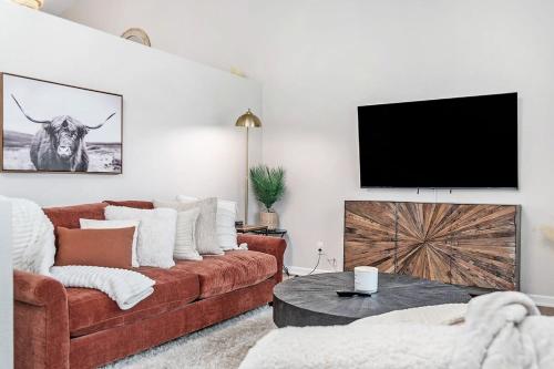 a living room with a brown couch and a flat screen tv at Elegant Escape-Fenced Yard BBQ & Cozy Fire Pit in Omaha