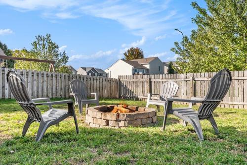 three chairs and a fire pit in a yard at Elegant Escape-Fenced Yard BBQ & Cozy Fire Pit in Omaha