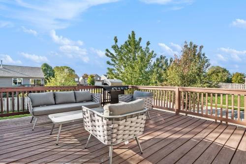 a deck with couches and chairs on a wooden deck at Elegant Escape-Fenced Yard BBQ & Cozy Fire Pit in Omaha