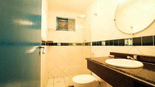 a bathroom with a sink and a toilet and a mirror at Casa da Nina | Beira-mar in Tamandaré