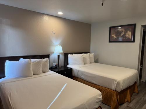 a hotel room with two beds with white sheets at Travelodge by Wyndham Sacramento / Rancho Cordova in Sacramento