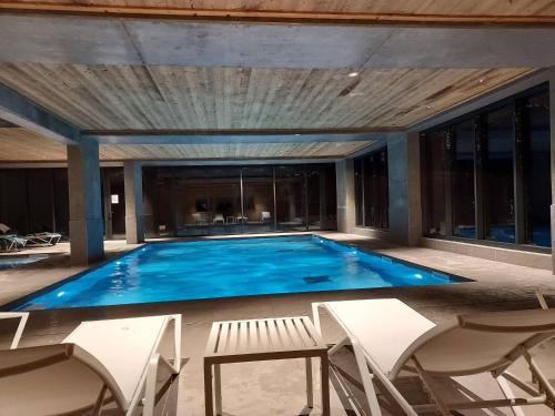 une grande piscine entourée de chaises blanches. dans l'établissement Appt cosy 75m², piscine, spa, 2 chambres, skis aux pieds, vue panoramique Les Arcs 1600 - FR-1-461A-27, à Arc 1600