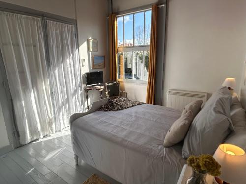 une chambre avec un lit et une grande fenêtre dans l'établissement Villa au Cap Ferret à 80mts de la plage et le marché, à Lège-Cap-Ferret
