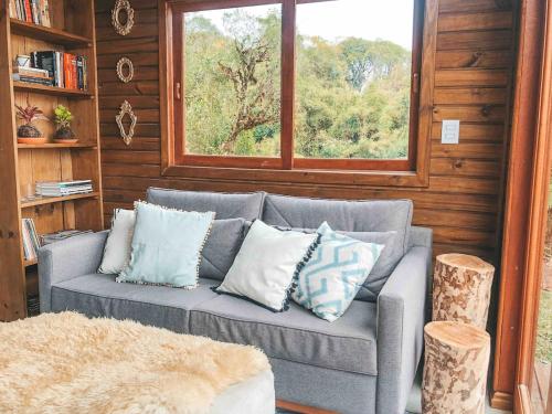 a couch with pillows in a room with a window at Quinta Alta Vista - Cabana Xaxim com jacuzzi e vista incrível in Rancho Queimado