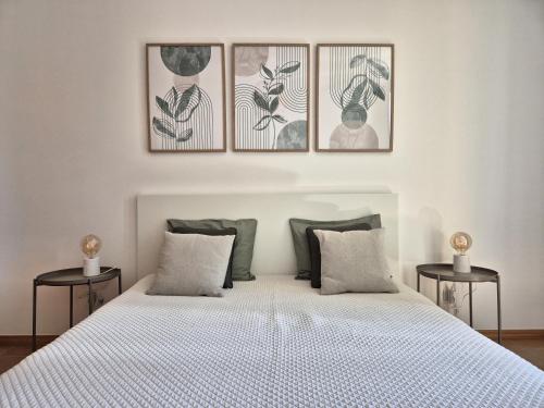 ein Schlafzimmer mit einem weißen Bett mit vier Bildern an der Wand in der Unterkunft Cantinho do Porto Santo in Porto Santo