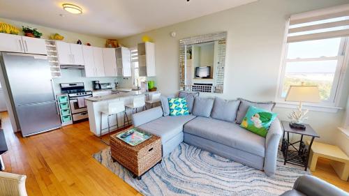 a living room with a couch and a kitchen at The One in Folly Beach