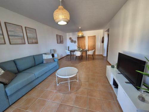 a living room with a blue couch and a tv at Cantinho do Porto Santo in Porto Santo