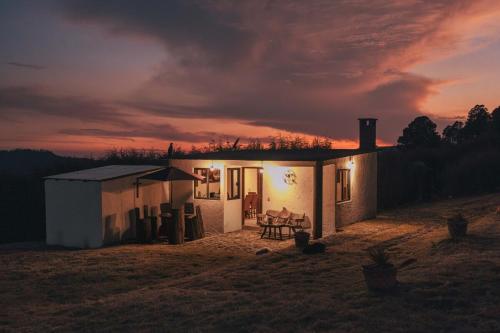 a small white house with a sunset in the background at Cabaña en el Ajusco, experiencia única en la naturaleza in Caseta Forestal