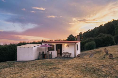a small white shed in a field with a sunset at Cabaña en el Ajusco, experiencia única en la naturaleza in Caseta Forestal