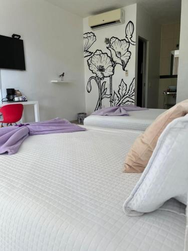 two white beds in a bedroom with a flower mural on the wall at Rancho Macloy Hotel Spa & Social Events in Yautepec