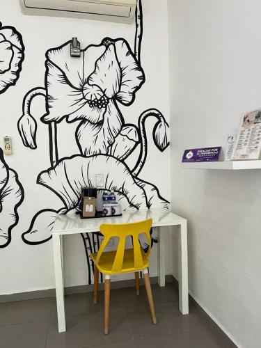 a table with a yellow chair and a wall with a flower mural at Rancho Macloy Hotel Spa & Social Events in Yautepec