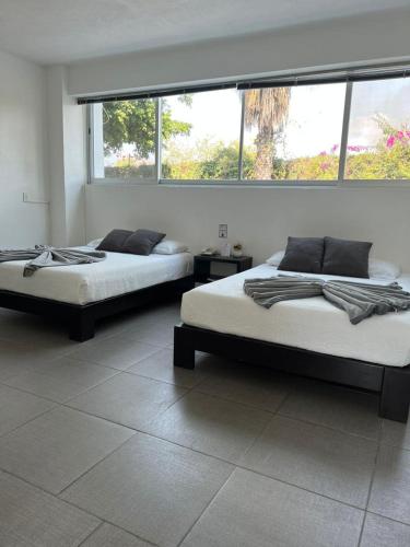 two beds in a room with two windows at Rancho Macloy Hotel Spa & Social Events in Yautepec