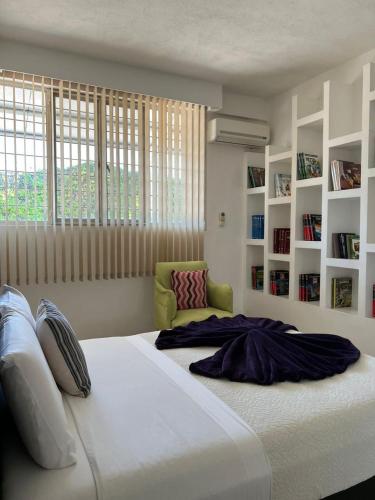 a bedroom with a large white bed and bookshelves at Rancho Macloy Hotel Spa & Social Events in Yautepec