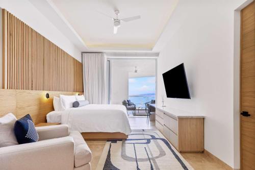 a bedroom with a bed and a tv and a couch at 2 Bedroom Residence with Terrace & Grill Live Aqua La Paz in La Paz