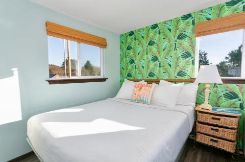 a white bed in a room with green walls and windows at Breakwater Resort in Grayland