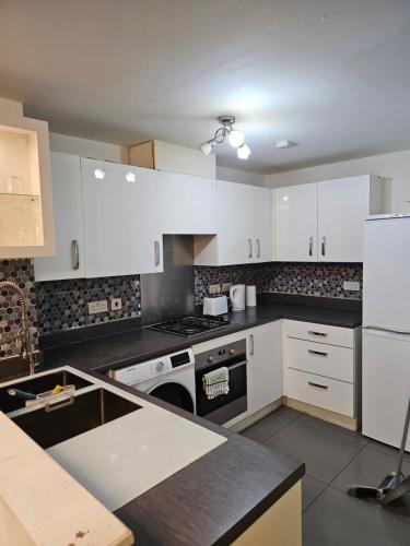 a kitchen with white cabinets and a stove top oven at Double Cosy Bedroom in Central Dartford in Dartford