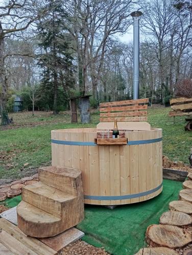 a wooden hot tub and a bench in a park at La maison du pêcheur in Saint-Justin