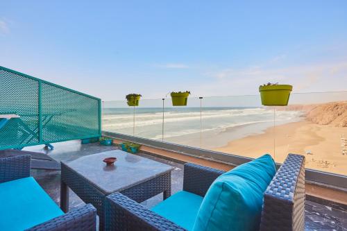 a balcony with a table and chairs and a beach at Amwaj Apt - Surf and Fun Beachfront Stay With Balcony in Mirleft