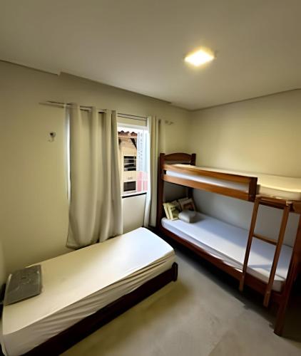 zwei Etagenbetten in einem Zimmer mit Fenster in der Unterkunft Casa BAM - 5 quartos, piscina e churrasqueira in Barra Grande