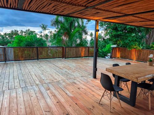 eine Holzterrasse mit einem Holztisch und Stühlen in der Unterkunft Villa Vista in Las Terrenas