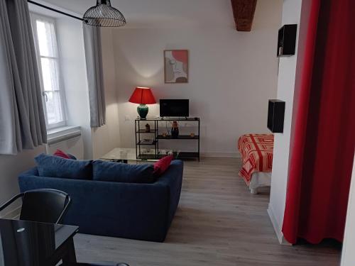 a living room with a blue couch and a bed at Studio Zoé in Saint-Père