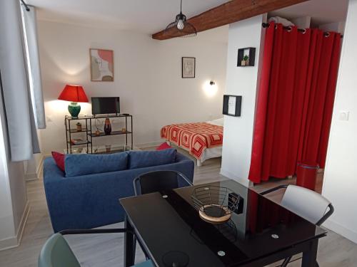 a living room with a blue couch and a red curtain at Studio Zoé in Saint-Père
