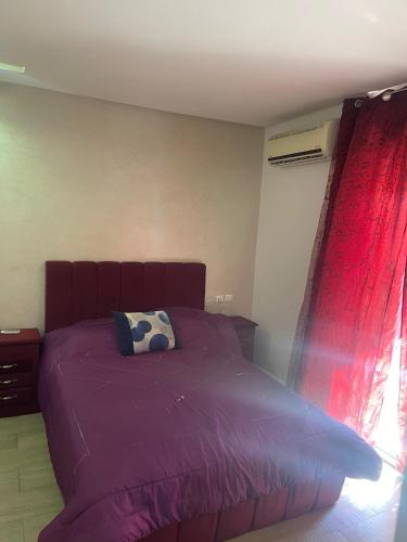 a bedroom with a purple bed with a pillow and a window at Votre Repaire Calme, Confort et Convivialité in Kenitra