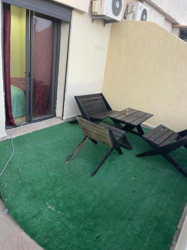 a patio with a table and chairs on a green floor at Votre Repaire Calme, Confort et Convivialité in Kenitra
