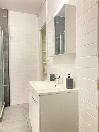 une salle de bain blanche avec un lavabo et un miroir dans l'établissement Havre de Lens - Centre-ville - 100m de la gare, à Lens