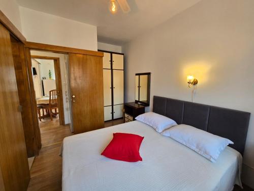 a bedroom with a white bed with a red pillow on it at Apartmani ROVINJEZ Komiza in Komiža