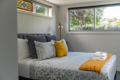 Un dormitorio con una cama con almohadas y una ventana. en North Road Retreat, en Dunedin