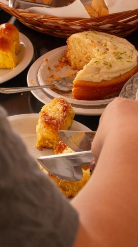 a person is eating a piece of cake on plates at Pousada Velas do Forte in Cabo Frio