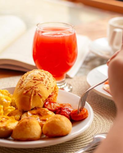 a plate of breakfast food and a drink on a table at Pousada Velas do Forte in Cabo Frio