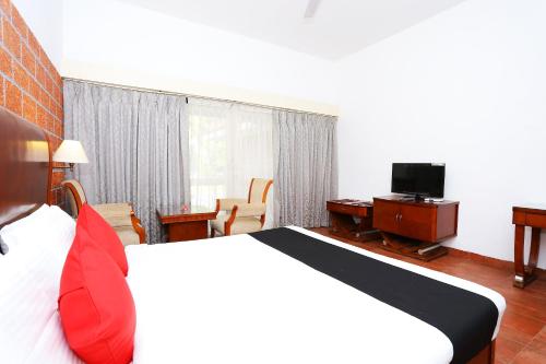 a hotel room with a bed and a desk and a television at Super Townhouse Island Inn in Cochin