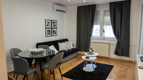 a living room with a black couch and a table at Apartman Innocence Sajam in Novi Sad