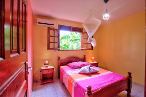 1 dormitorio con cama con sábanas rosas y ventana en Villa Bouillante, en Bouillante