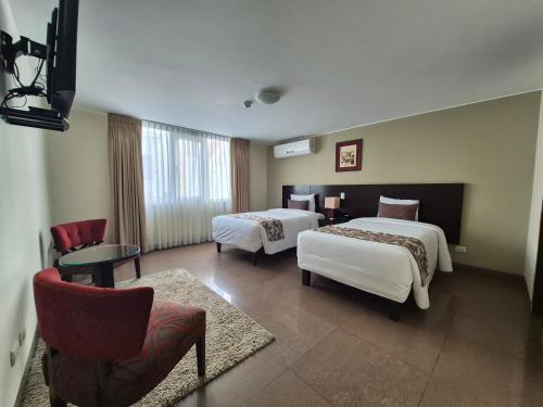 a hotel room with two beds and a chair at El Tambo 1 in Lima