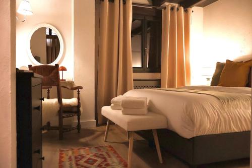 une chambre avec un lit, une chaise et un miroir dans l'établissement Lodge du Monthury, à Servance