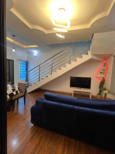 Una sala de estar con un sofá y una escalera. en Cozy Duplex with garden, en Iju Junction