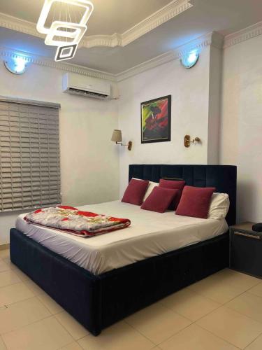 Un dormitorio con una cama grande con almohadas rojas. en Cozy Duplex with garden, en Iju Junction