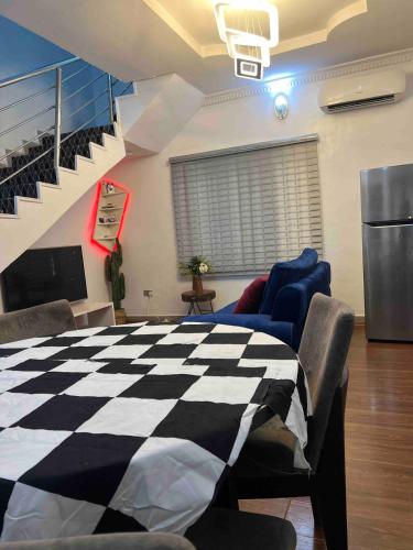 una sala de estar con mesa y sillas a cuadros en Cozy Duplex with garden, en Iju Junction