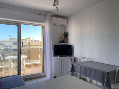 une chambre avec un lit, une télévision et un balcon dans l'établissement T1 avec terrasse, parking & climatisation à Balaruc-les-Bains - FR-1-553-283, à Balaruc-les-Bains