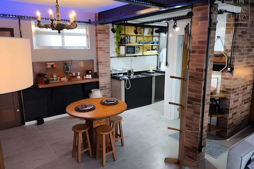 a kitchen with a wooden table and some stools at Apartamento Chalé da Ilha - Ar Cond e Super VISTA in São Vicente