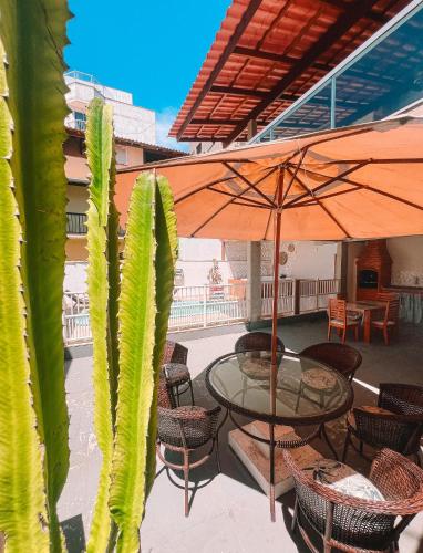 a patio with a table and chairs and an umbrella at Pousada Velas do Forte in Cabo Frio